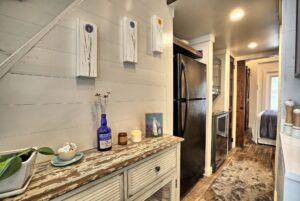 Rustic kitchen at 132 Drifting Brook with black fridge, wood floors, floral decor; leads to bedroom—charming real estate find.