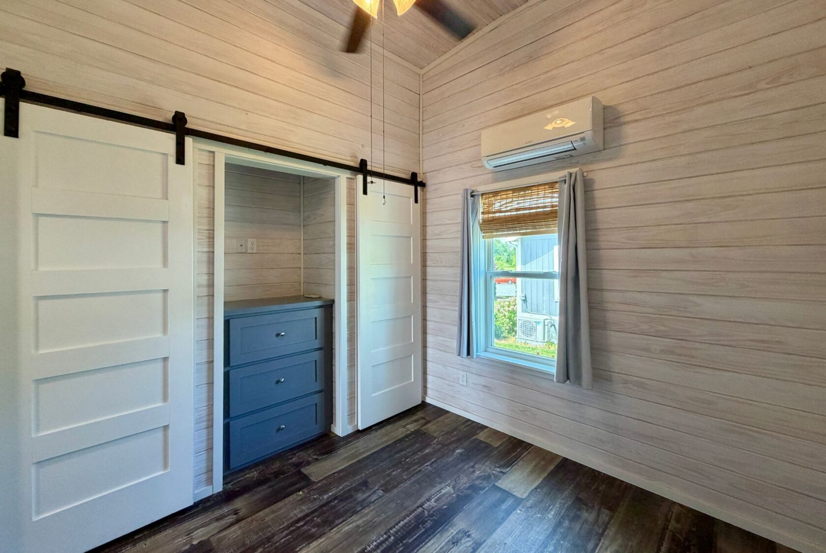 Small room with wood panel walls, sliding barn doors, and blue drawers—perfect for strolling down the Easy Lane.