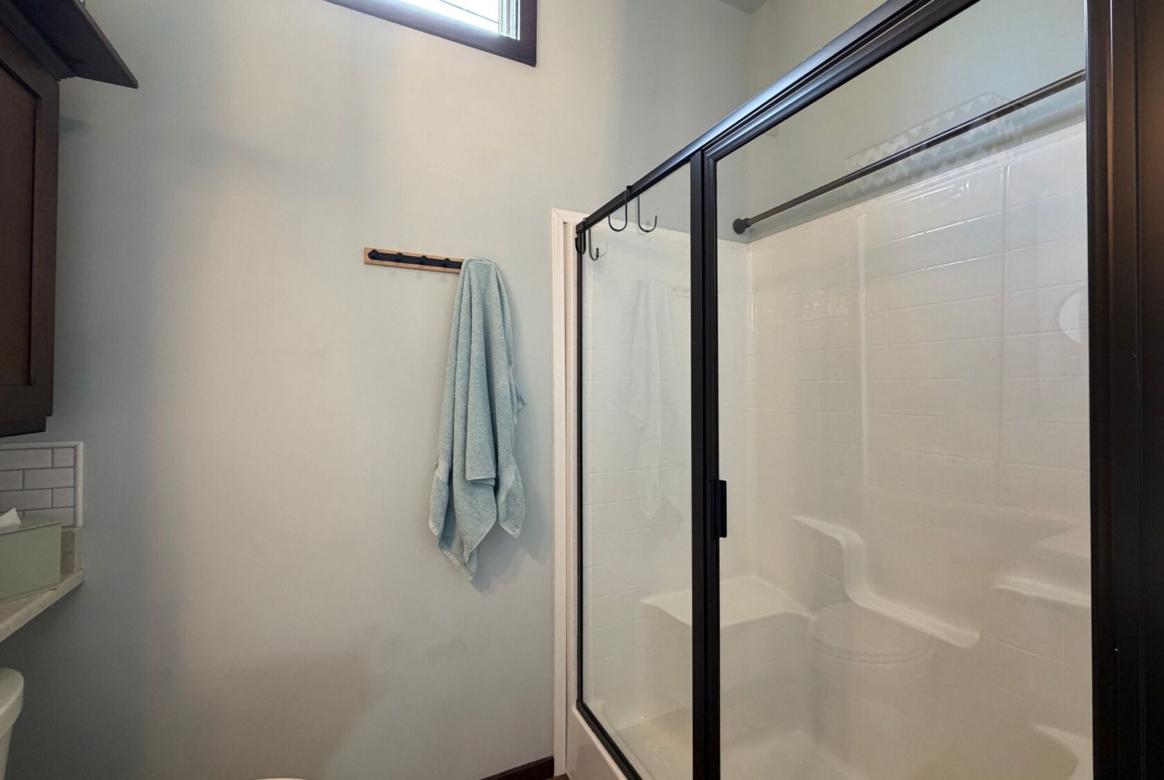 Modern bathroom at 59 Drifting Brook with glass shower, white tile, and two blue towels on a wall hook.