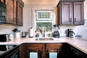 A cozy kitchen at 132 Drifting Brook Lane features dark wood cabinets, a sink under a window, and white countertops.