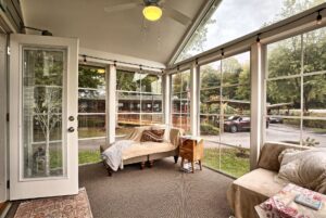 Bright sunroom with large windows, cozy seating, and a view at 132 Drifting Brook—perfect real estate opportunity.