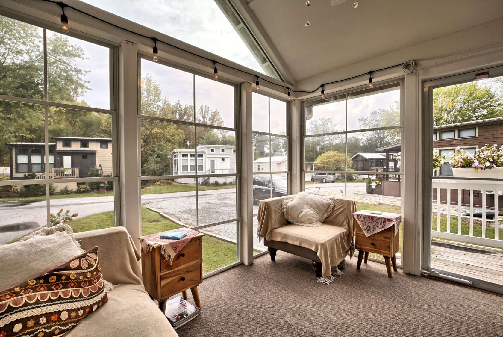 A cozy sunroom with large windows, armchairs, and views of a trailer park on Drifting Brook Lane.