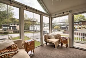 A cozy sunroom with large windows, armchairs, and views of a trailer park on Drifting Brook Lane.