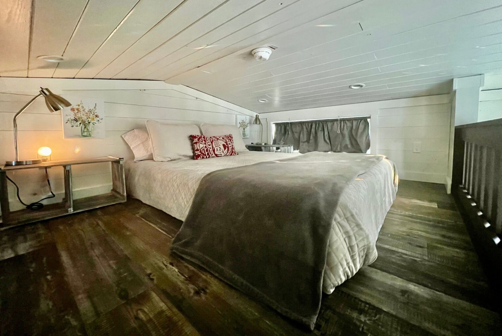 Cozy loft bedroom at 132 Drifting Brook Lane with a low ceiling, double bed, bedside lamp, and rustic wooden floors.