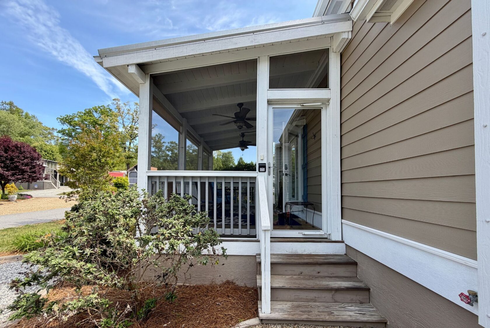Screened porch with steps, white railing, ceiling fan, and tan siding at 59 Drifting Brook on a sunny day.