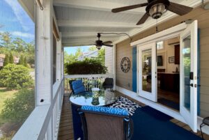 Screened porch at 59 Drifting Brook, with ceiling fans, glass table, chairs, rug, and open double doors leading inside.
