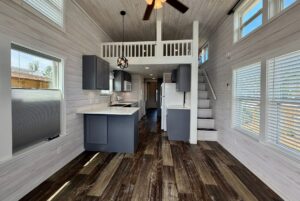 Modern tiny house interior with loft, kitchen, and large windows—perfect for Strolling Easy Lane living.