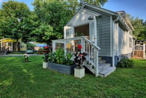 Charming small gray house with glass porch and flower planters at 132 Drifting Brook Lane, surrounded by trees.