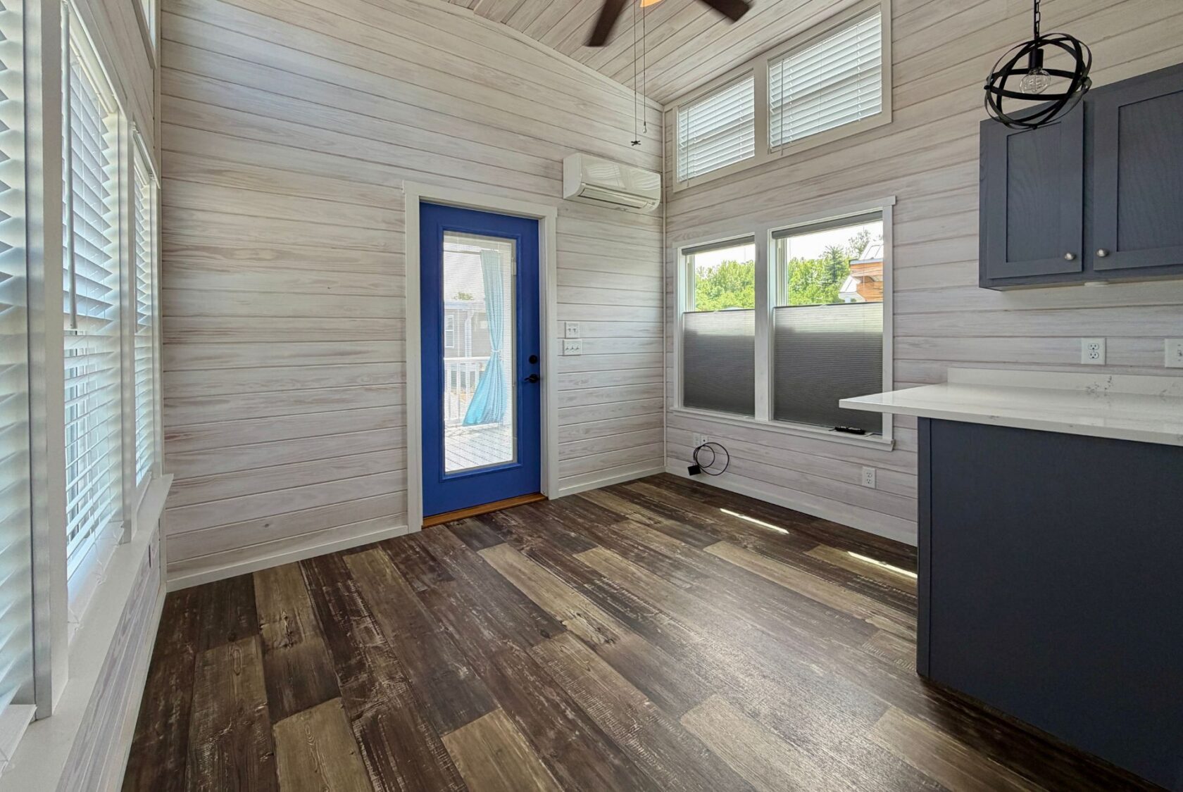 Bright, modern room with wood floors and a blue door—perfect for Strolling Easy Lane beside the kitchen counter.