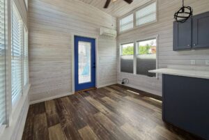 Bright, modern room with wood floors and a blue door—perfect for Strolling Easy Lane beside the kitchen counter.