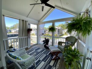 Bright screened porch with wicker chairs and plants at 43 Skipping Stone Lane, overlooking a sunny neighborhood street.