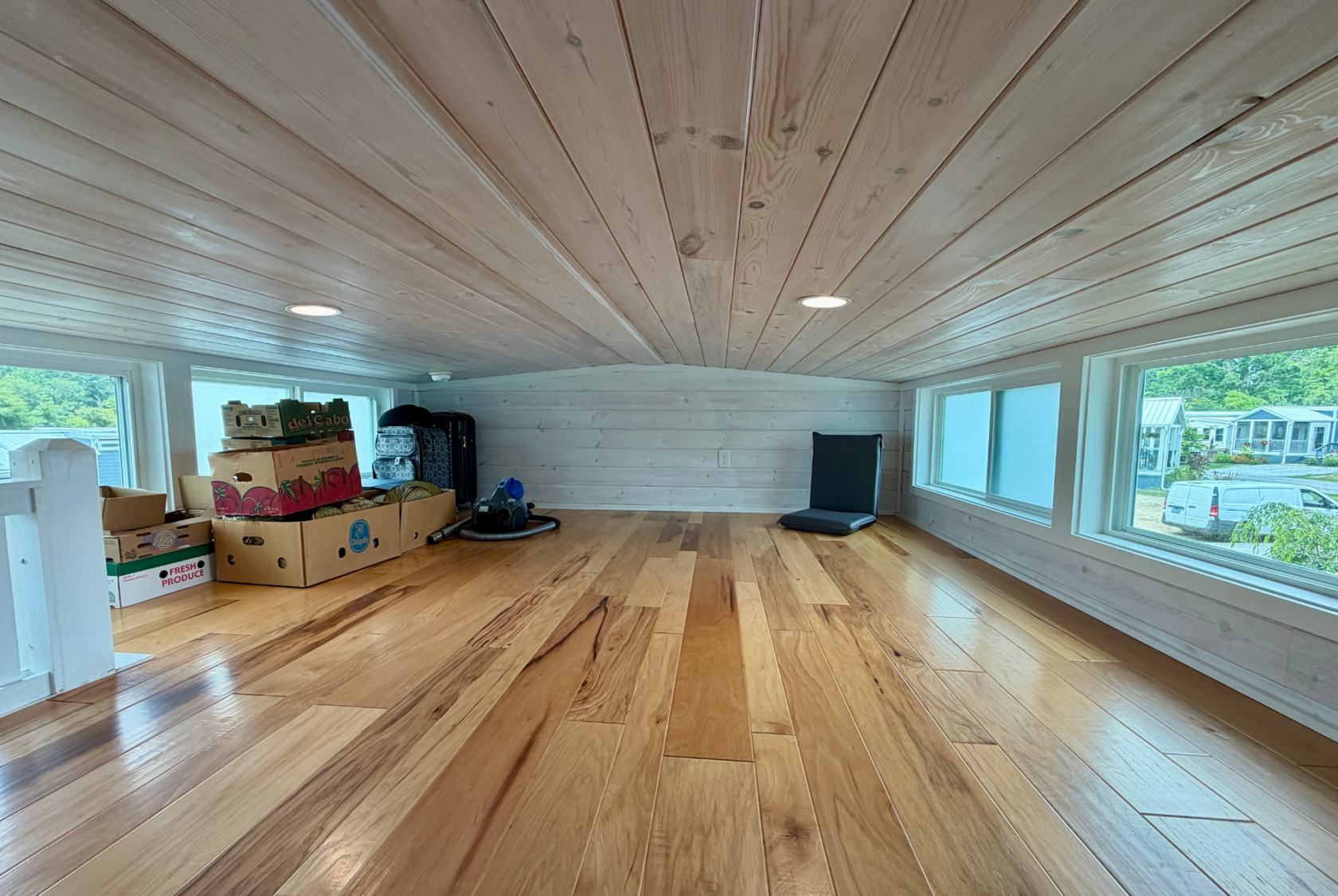 Loft on Mount Meadow Lane with wood floors and ceiling, storage on the left, windows on both sides, natural light.
