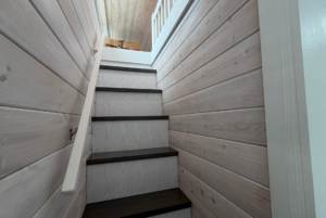 Wood-paneled staircase with a handrail, leading up to a landing with cardboard boxes on Mount Meadow Lane.
