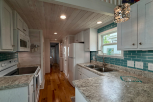 Modern Mount Meadow Lane kitchen with turquoise tile backsplash, white cabinets, marble counters, and wood floors.