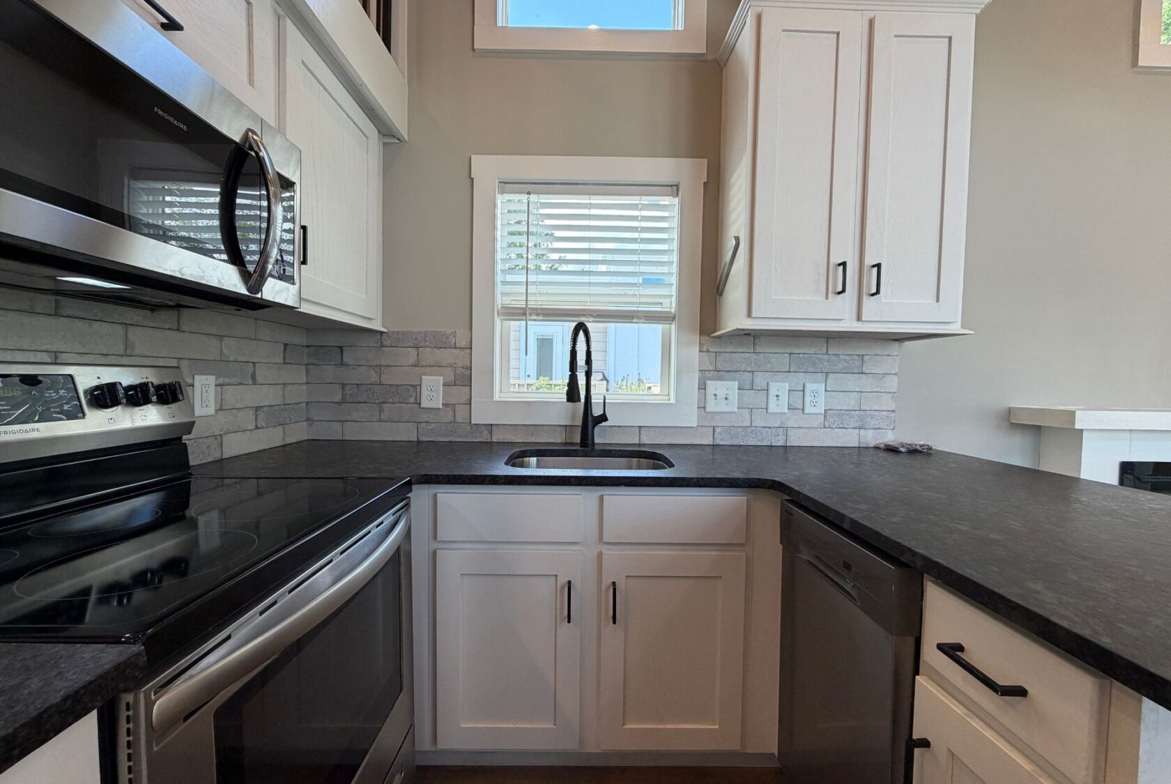 Modern kitchen at 103 Meandering Lane with white cabinets, black countertops, and stainless appliances.