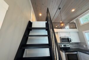 A black metal staircase at 103 Meandering Lane leads to a loft above a modern kitchen with white cabinets, steel appliances.