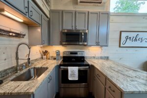 Modern kitchen on Highland Hill Lane with gray cabinets, marble countertops, and a charming "gather" sign.