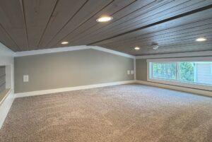 Cozy loft at 103 Meandering Lane with carpeted floor, gray walls, recessed lights, and a large window with tree views.