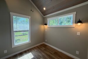 Charming room at 103 Meandering Lane with wood floor, gray walls, slanted ceiling, and two black wall sconces.
