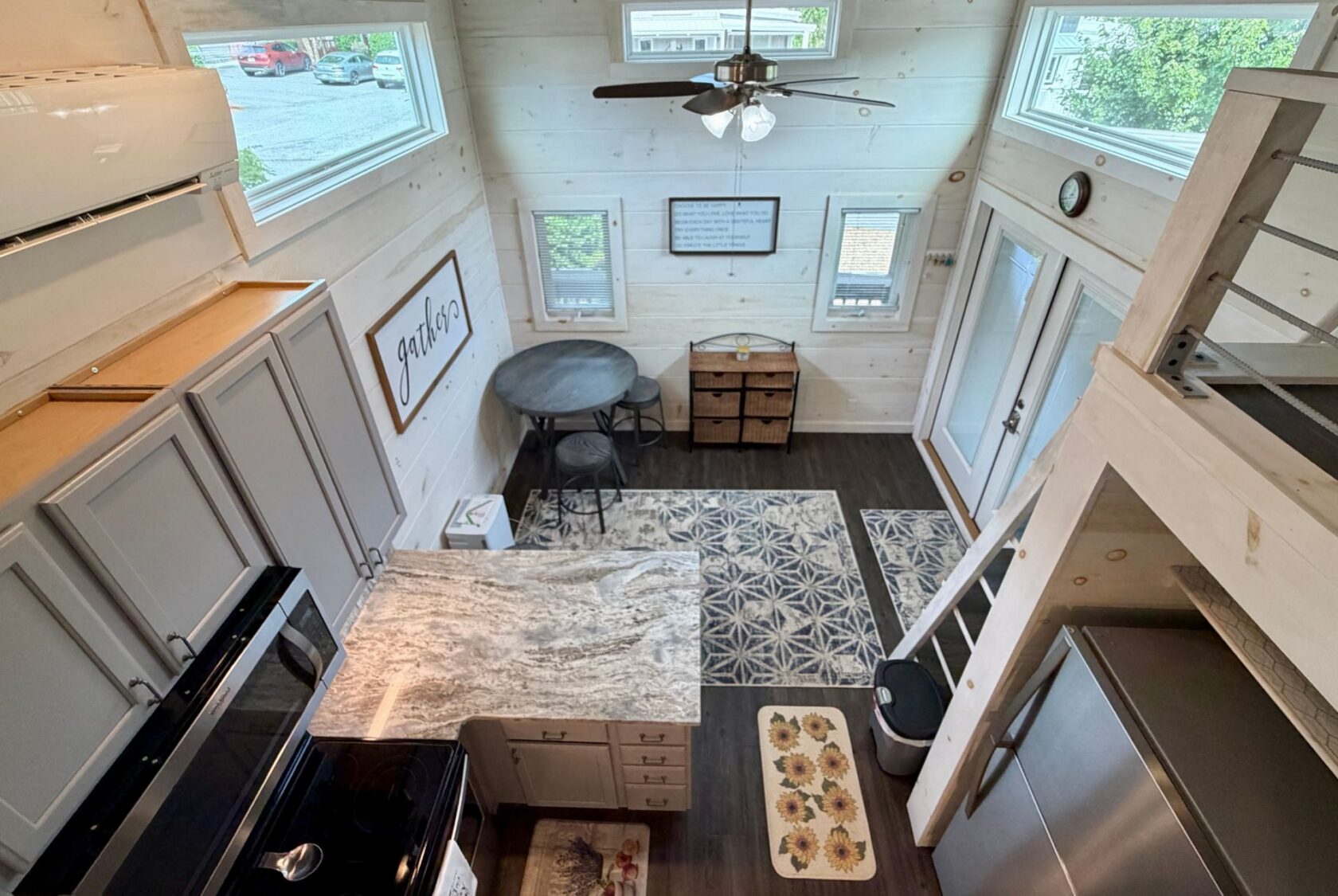 Discover 23 Highland Hill Lane: a tiny house featuring a kitchen, dining table, loft, stairs, and sunlit large windows.