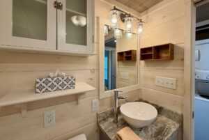 Modern Highland Hill Lane bathroom with vessel sink, granite counter, wall shelves, and a lighted mirror.
