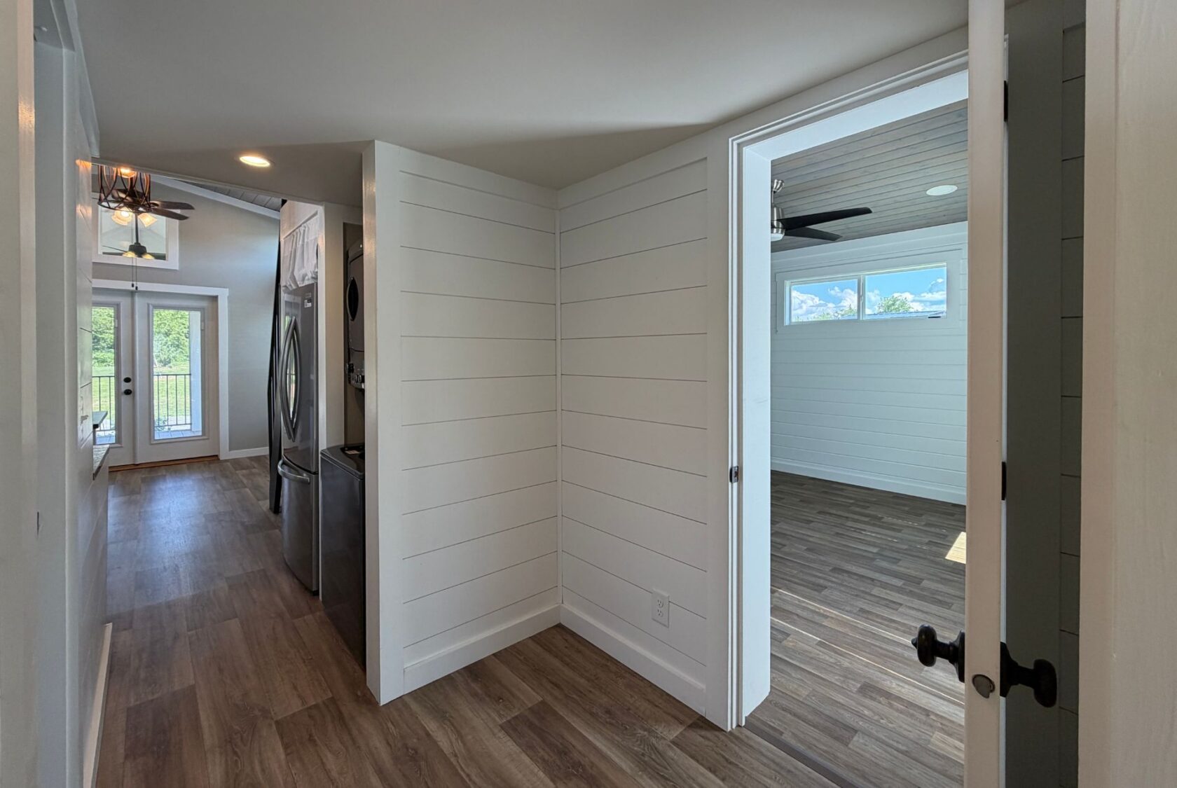 Hallway at 103 Meandering Lane with wood floors, white walls, laundry area, bedroom, and balcony access.