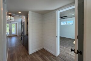 Hallway at 103 Meandering Lane with wood floors, white walls, laundry area, bedroom, and balcony access.