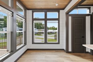 Bright room with large windows, wood floor, white walls, and dark trim, overlooking a small neighborhood.