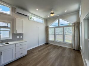 Bright room on Meandering Lane with large windows, white cabinets, wood floor, and abundant natural light.