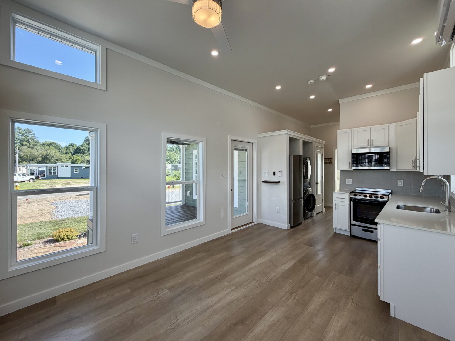 Modern kitchen at 100 Meandering Lane with white cabinets, stainless appliances, wood floors, and large windows.
