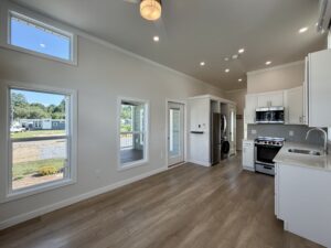 Modern kitchen at 100 Meandering Lane with white cabinets, stainless appliances, wood floors, and large windows.