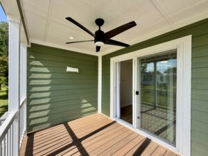 Small green porch with wood flooring on Meandering Lane, a black ceiling fan, and a glass sliding door leading inside.
