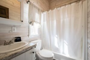 Small bathroom at 66 Empire Lane with a white sink, toilet, and tub, plus wood-paneled walls and a white shower curtain.