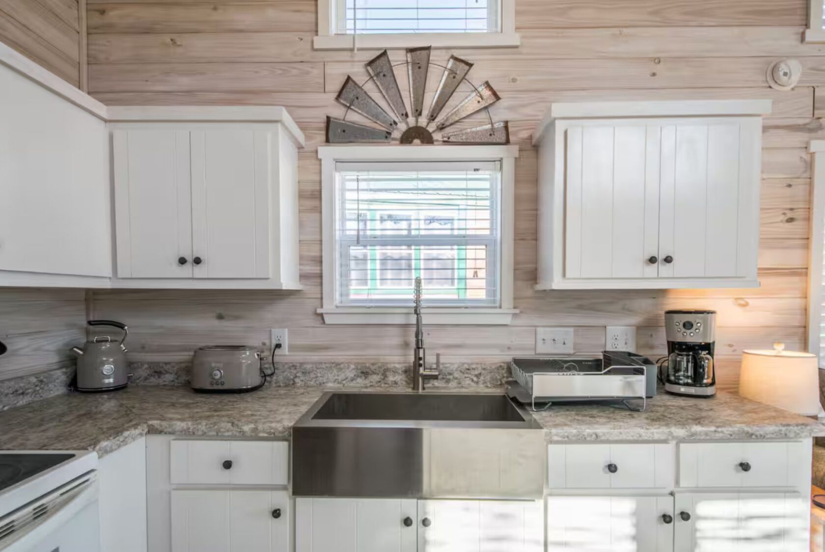 Modern farmhouse kitchen at 66 Empire Lane with white cabinets, stainless sink, and small appliances on marble countertop.