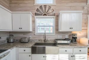 Modern farmhouse kitchen at 66 Empire Lane with white cabinets, stainless sink, and small appliances on marble countertop.